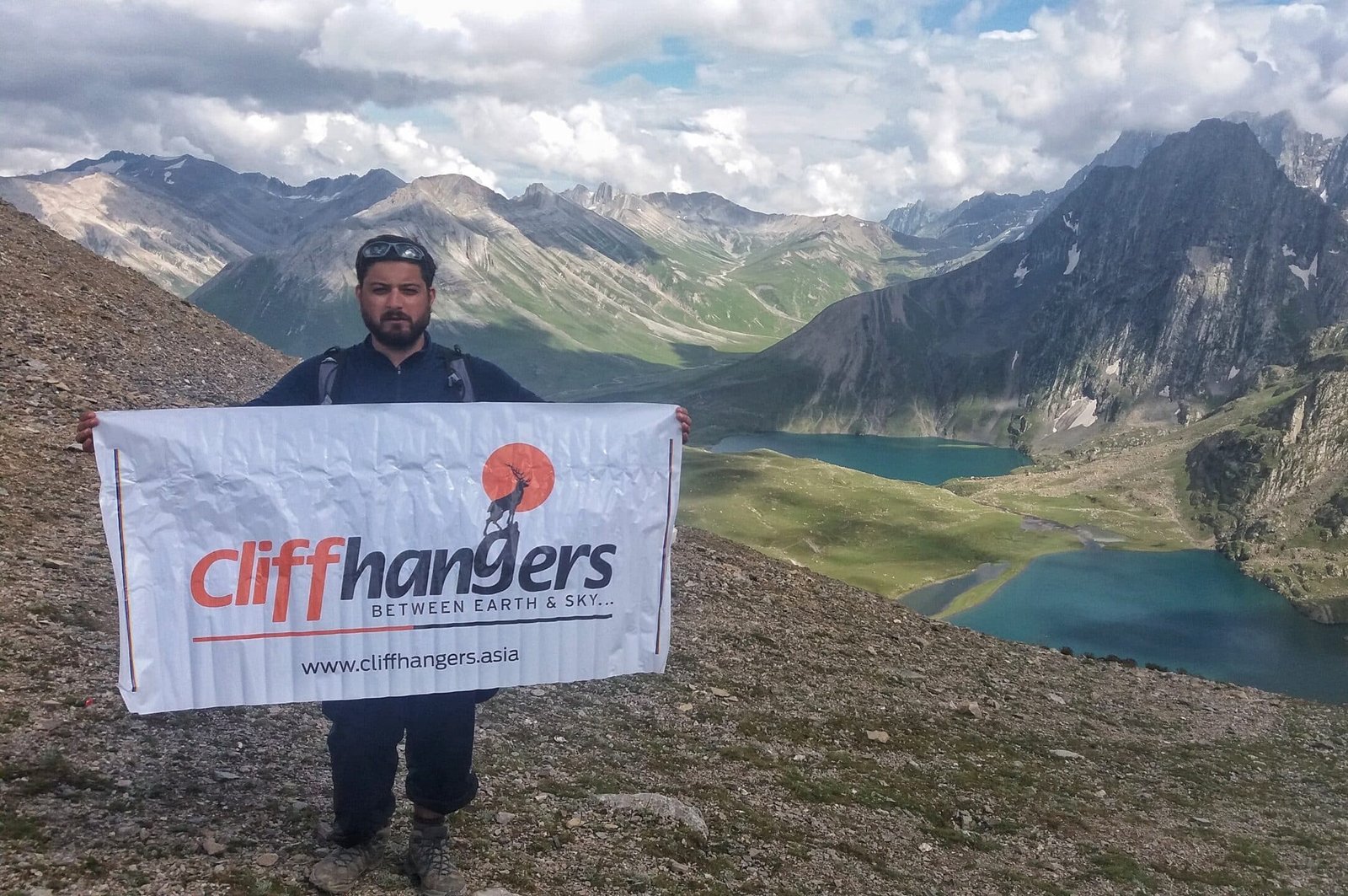 a trekker holding cliffhangers banner on kashmir great lakes trek