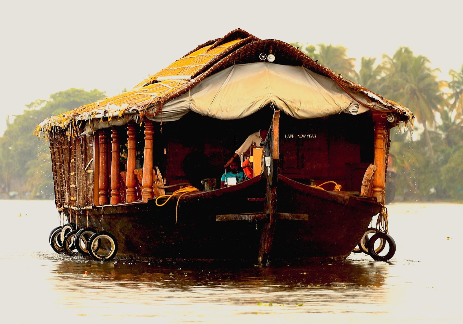 A traditional srinagar houseboat floating on backwaters with palm trees in the background
