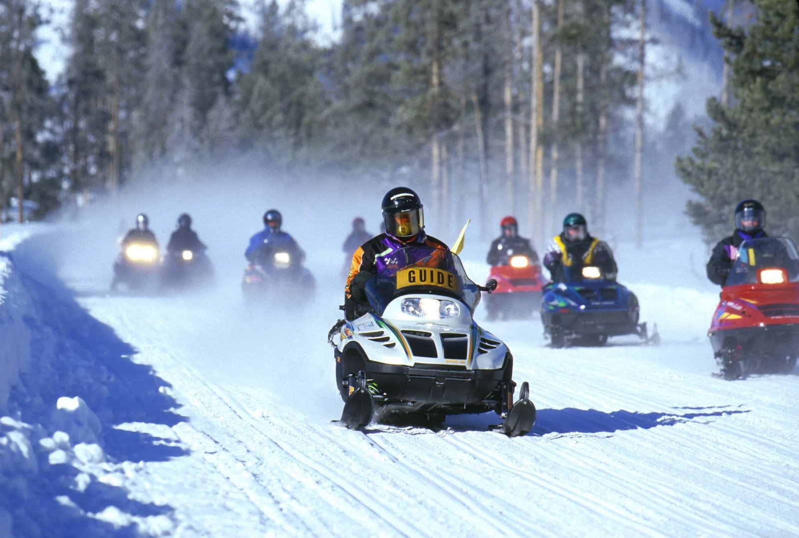 Tourists are racing on snowmobiles.