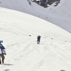 trekkers are climbing the snow-covered Harmukh Peak