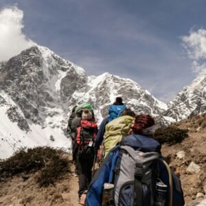 A group of trekkers with backpacks hiking on a narrow mountain trail during the Kedarkantha trek