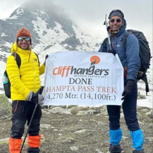 Trekkers posing with a summit banner on the Hampta Pass Trek route