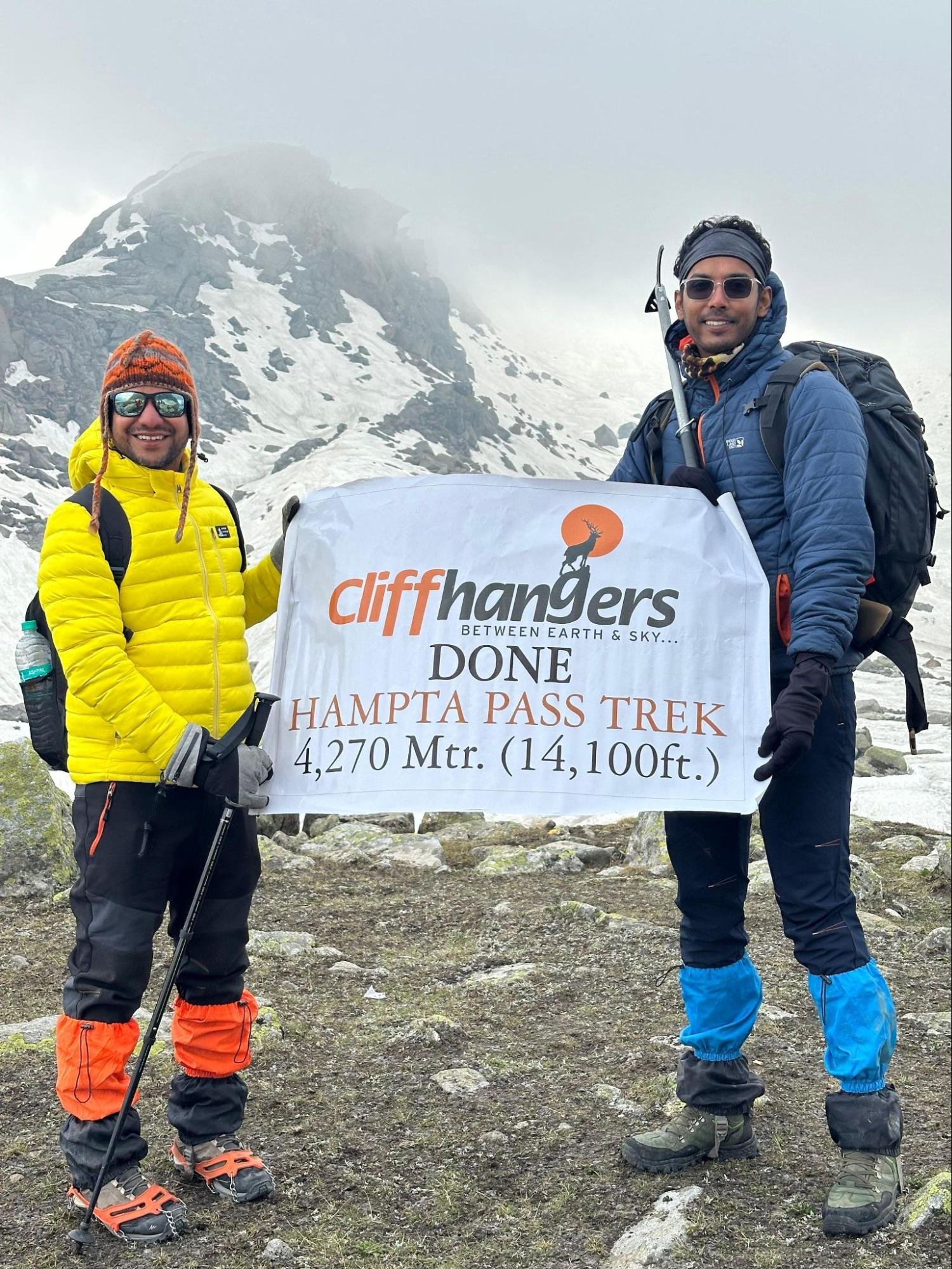 Trekkers posing with a summit banner on the Hampta Pass Trek route