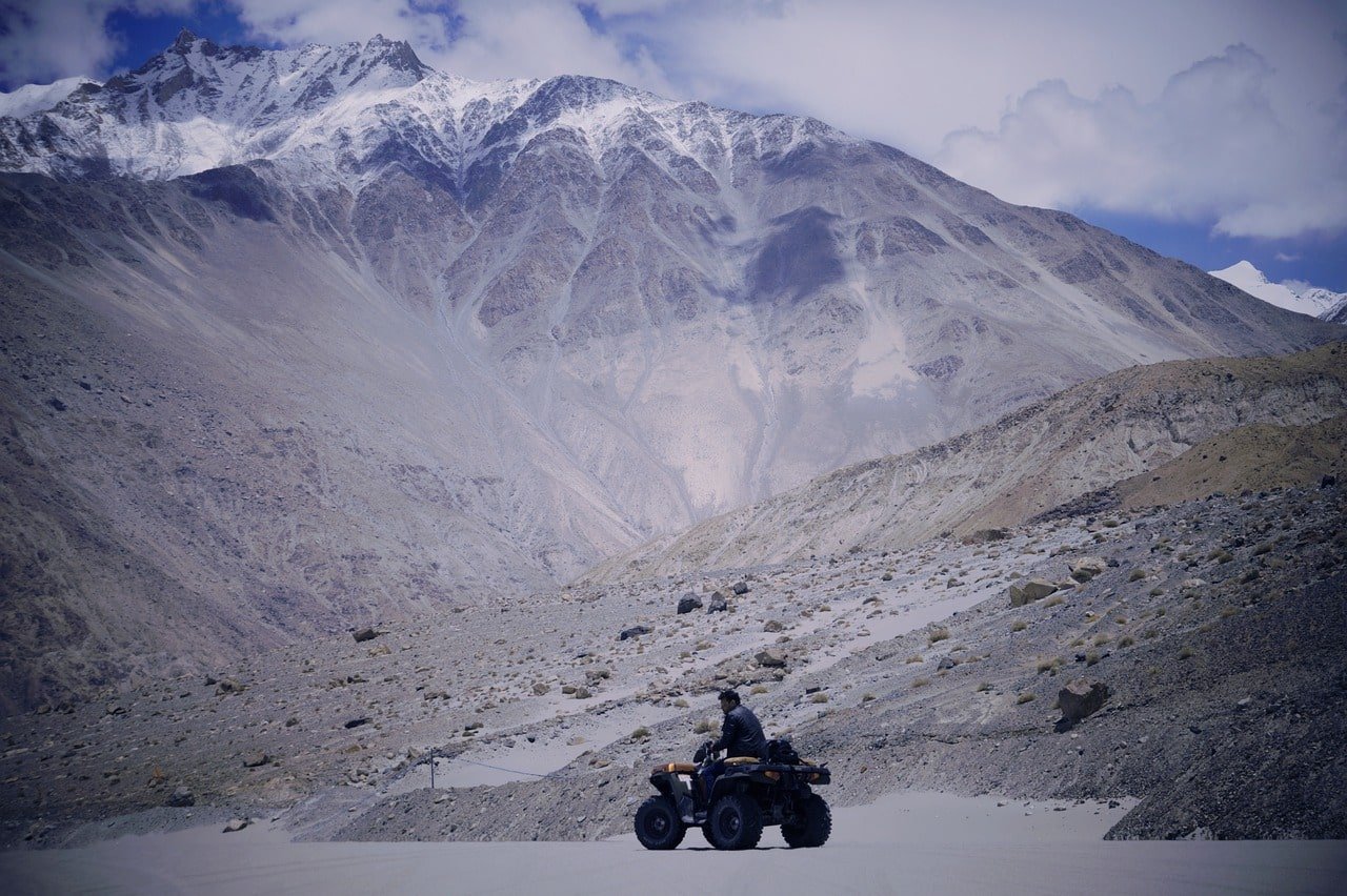 Person riding an ATV on a mountain trail in Manali under a twilight sky
