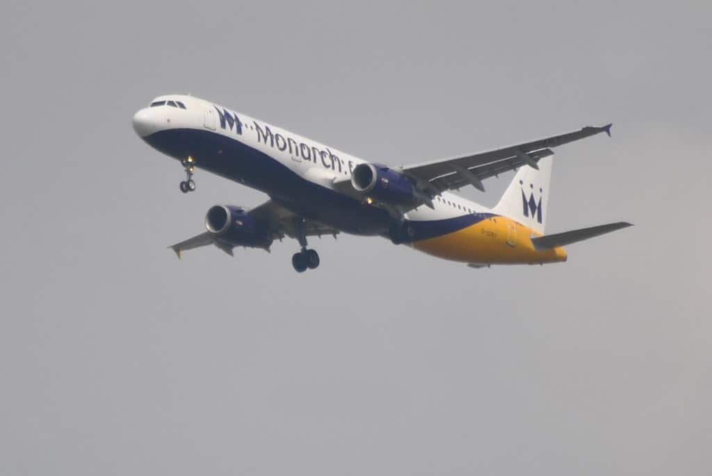 A Monarch Airlines plane in the sky with landing gear down