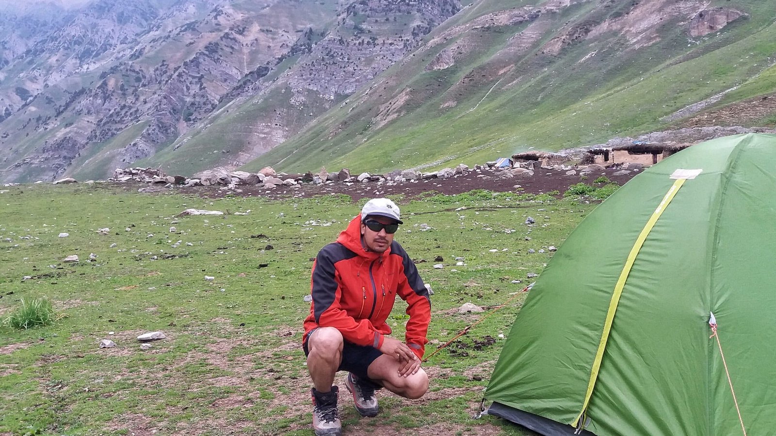 a trekker posing with his tent pitched on the meadows of Kashmir Great Lakes Trek