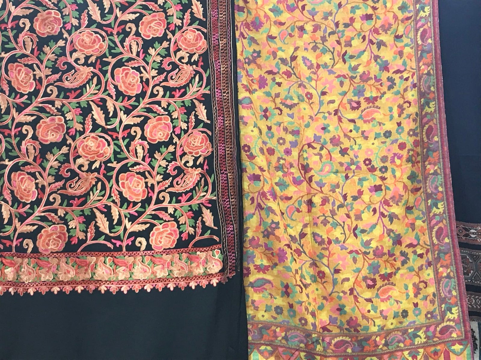 Two Kashmiri shawls with colorful floral embroidery.