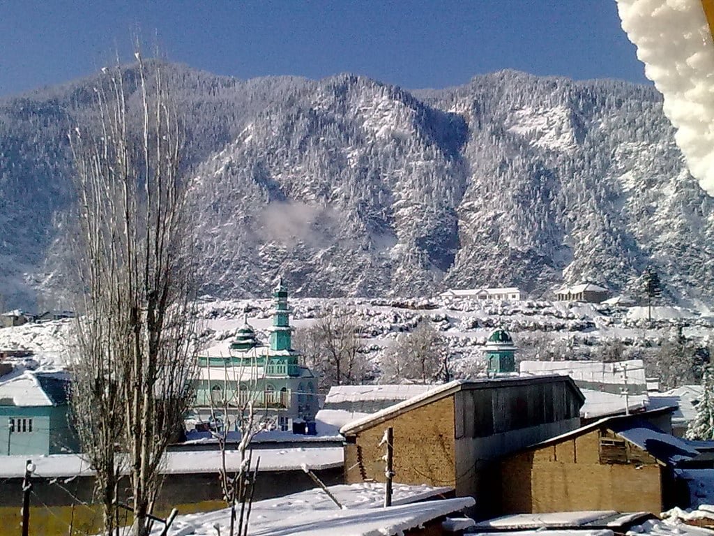 Snow-covered town with a mosque and mountains in the background