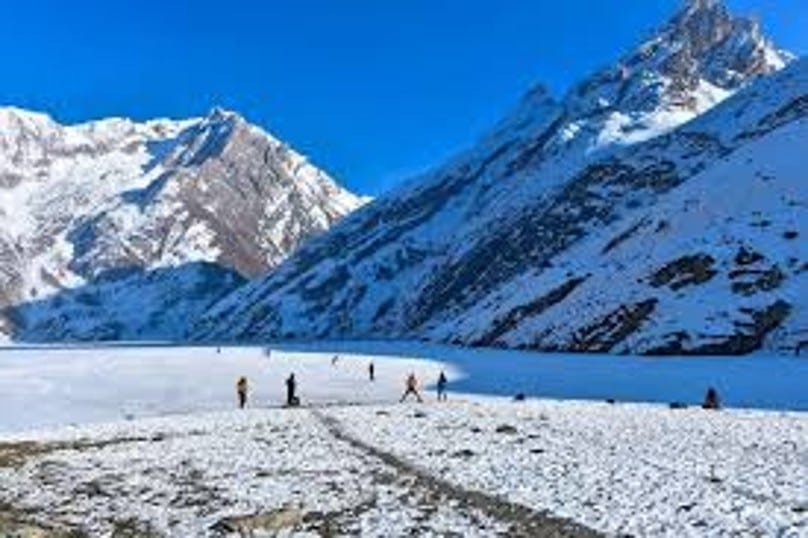 Frozen lake surrounded by snowy mountains with people walking on the ice