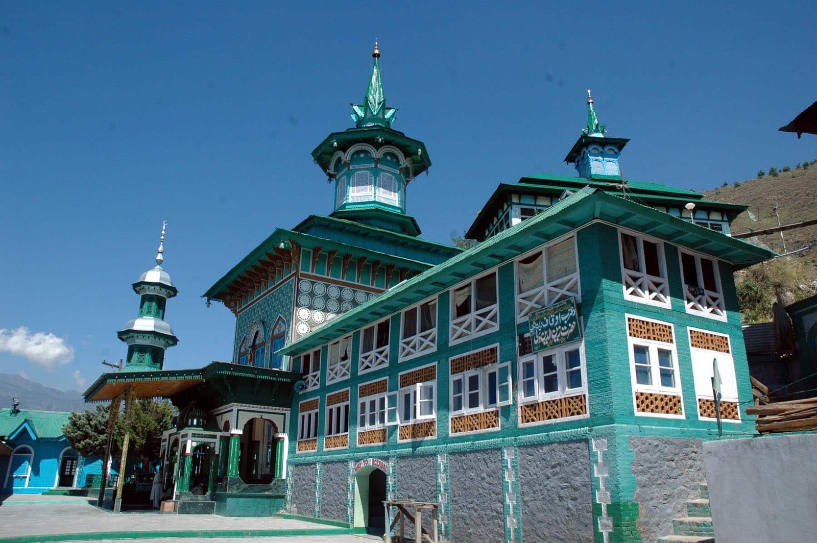 Colorful Aishmuqam Shrine with green and white architecture under blue sky