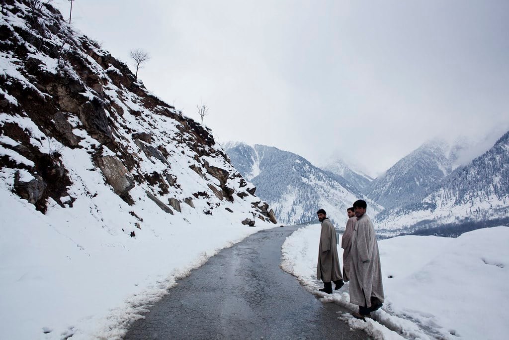 Four men walking on a snowy mountain road during the month of march in pahalgam