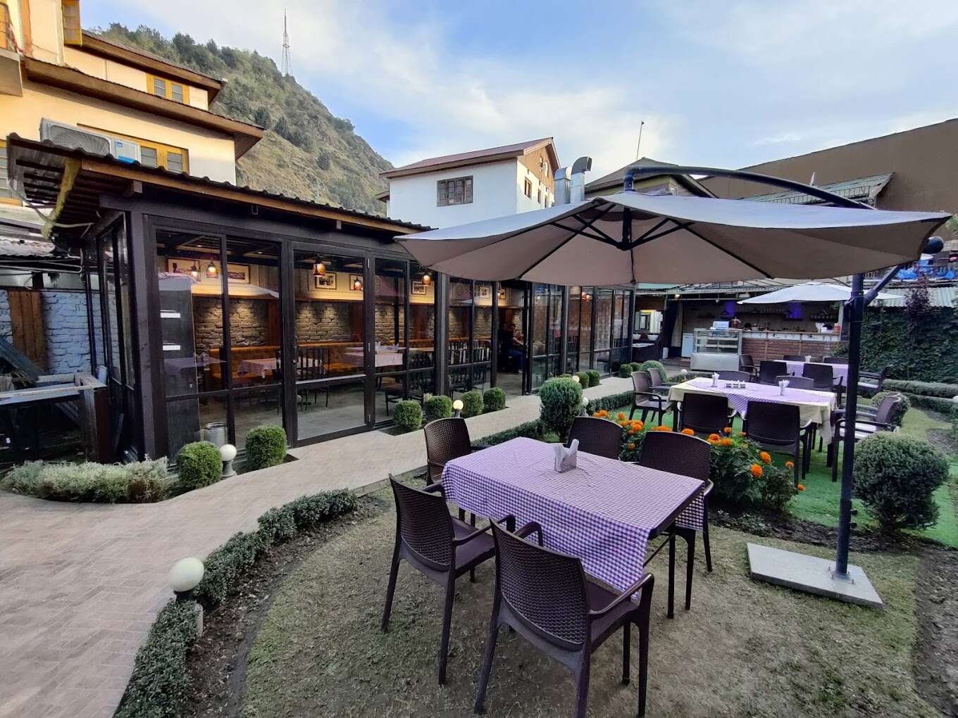 Outdoor dining at Lhasa, offering a peaceful garden setting with mountain views in srinagar
