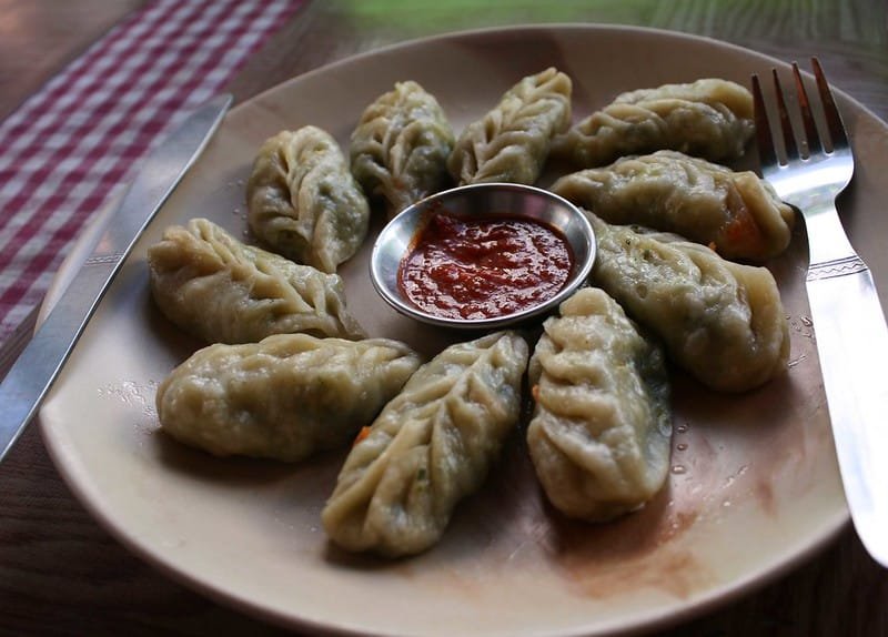 Plate of steamed momos with red chili sauce