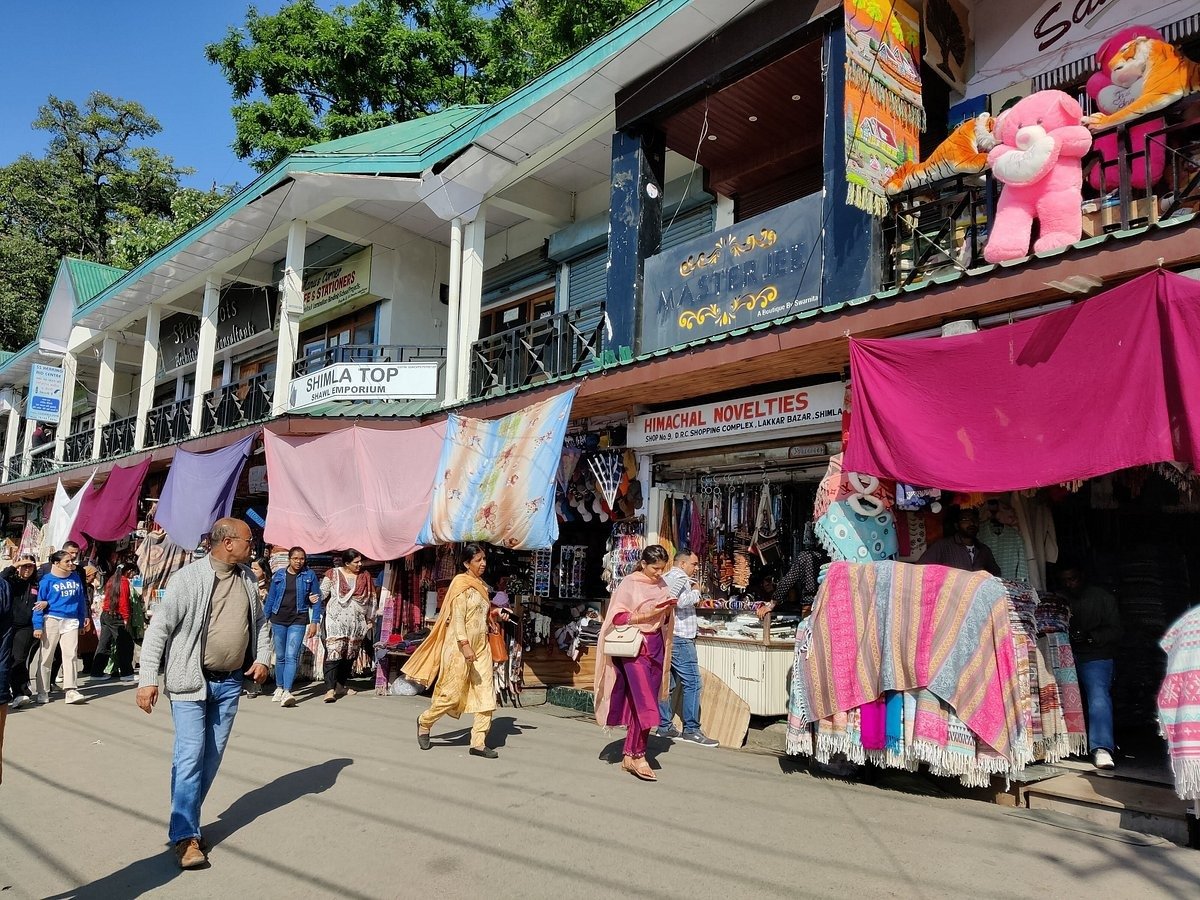 People walking past colorful shops and woolen stalls at Lakkar Bazaar in Shimla