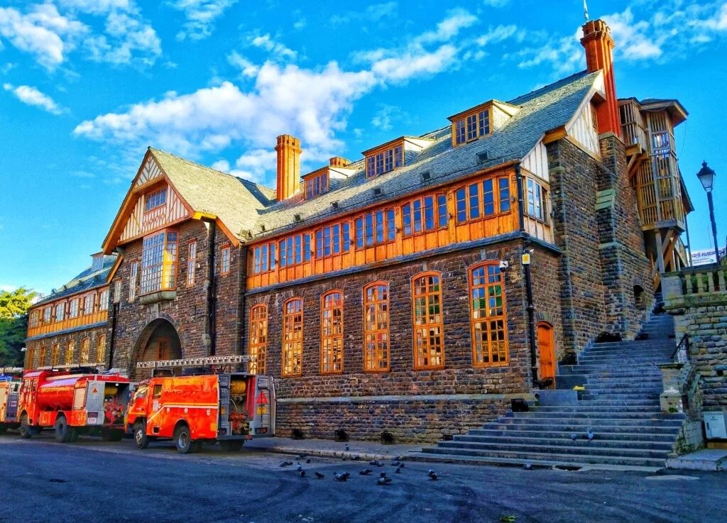 Gaiety Heritage Cultural Complex, a grand stone and wood building with arched windows and fire trucks parked in front