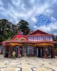 People entering a Kali Bari Temple under a partly cloudy sky