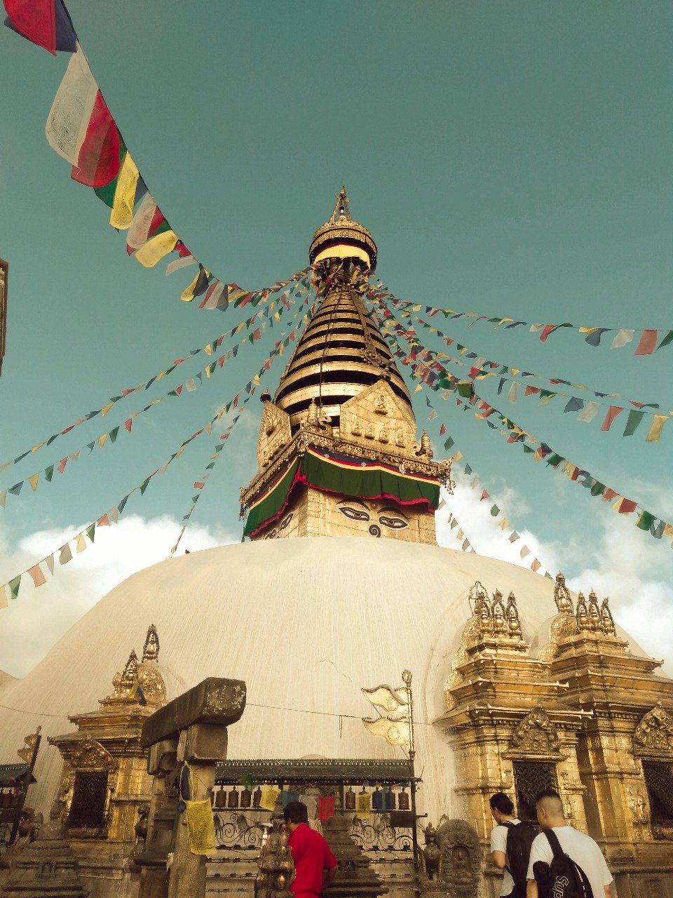 Takthok Gompa with colorful prayer flags and visitors at the entrance