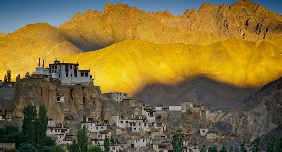 Lamayuru Monastery surrounded by traditional houses and dramatic mountains at sunset - one of the must-see places to visit in Leh.