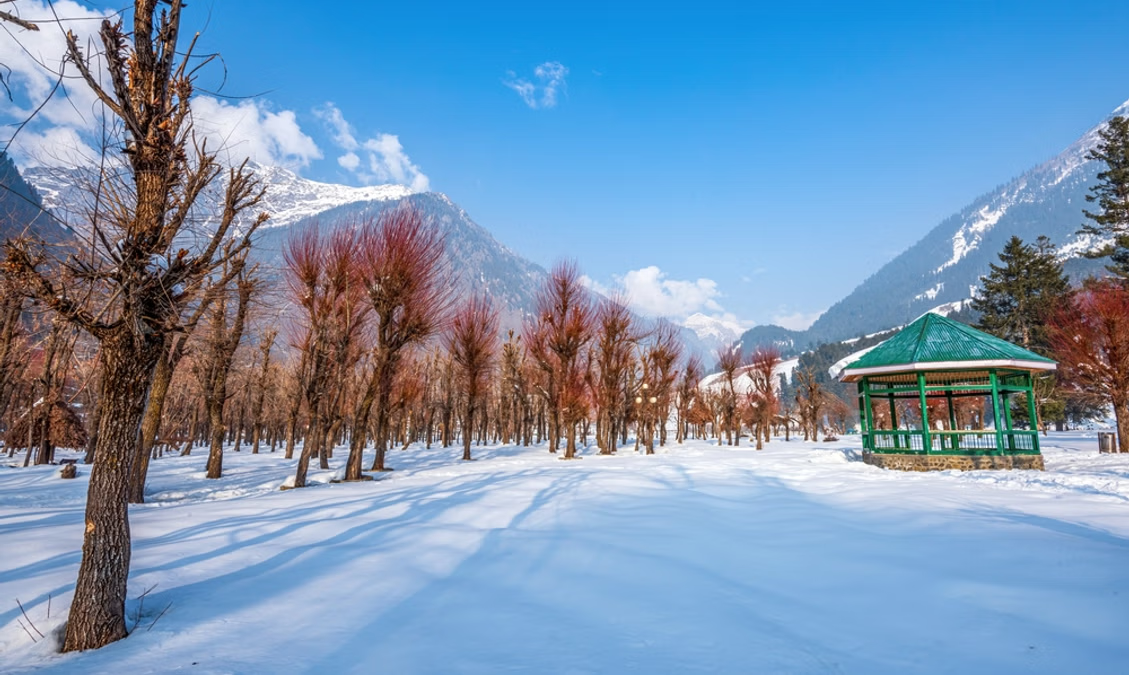 Snow-covered Pahalgam in February with bare trees and mountains.