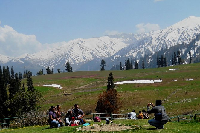 Tourists enjoying a picnic in Kashmir with snow-capped mountains in the background
