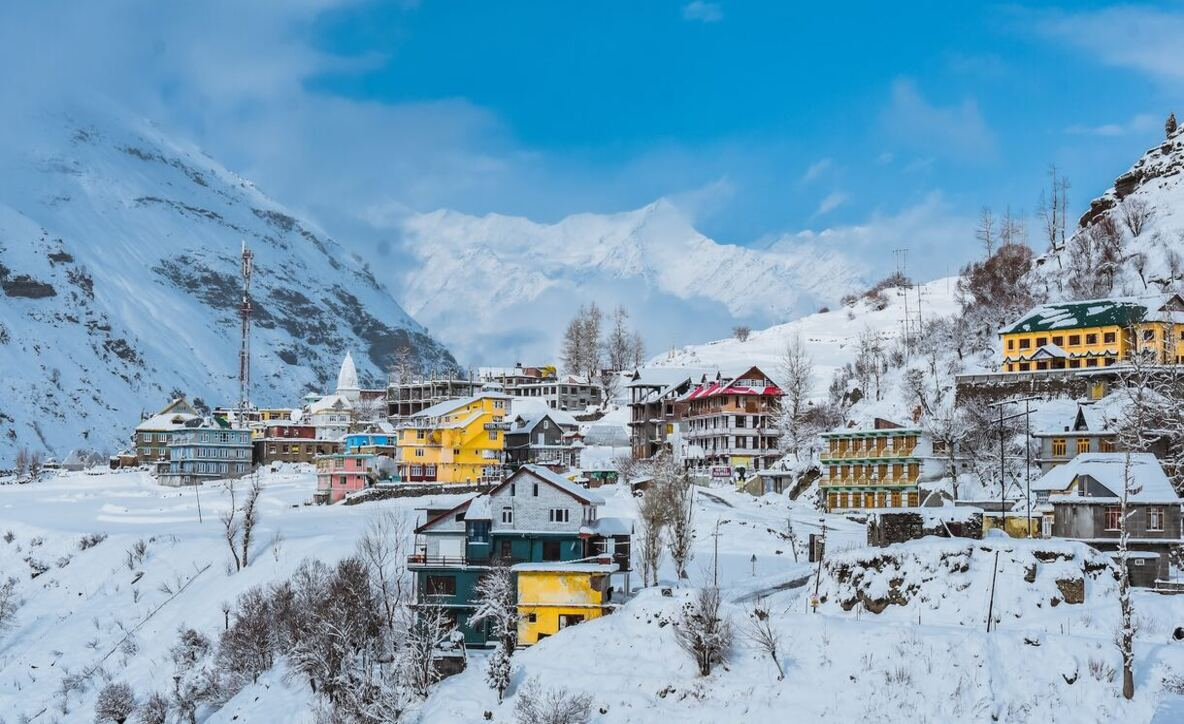 Snow-covered town of Manali with colorful buildings and mountain backdrop