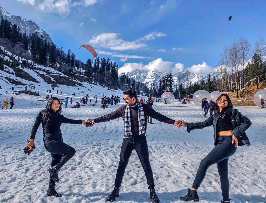 Tourists enjoying snow activities and paragliding in Manali